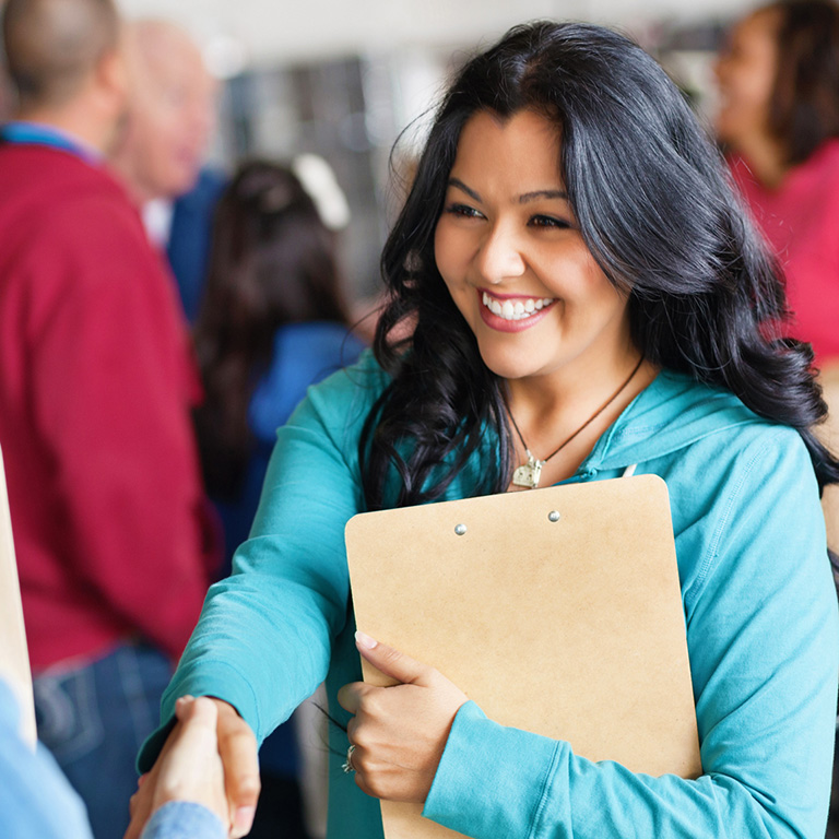 Female college student leader engaging on campus and shaking hands with another student