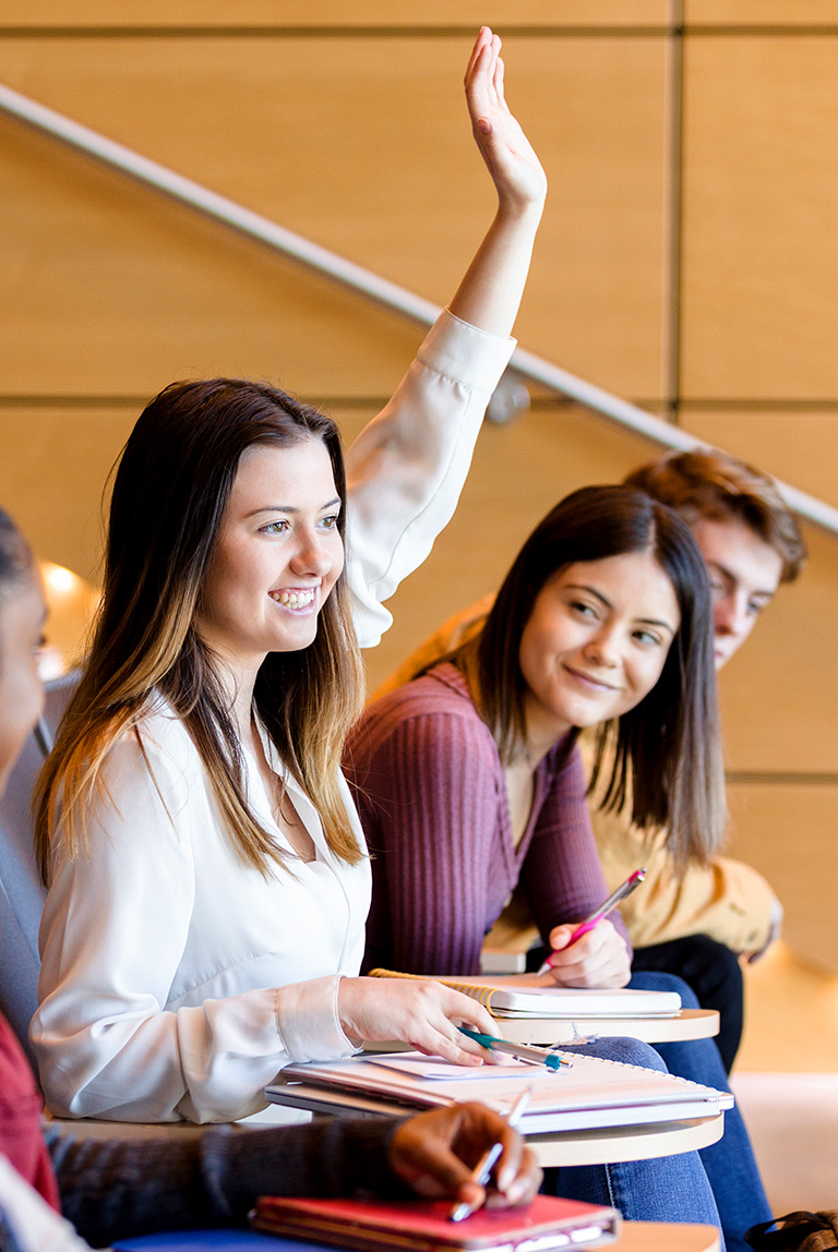 Female college student raising her hand in a lecture class
